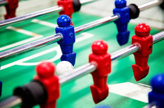 A player from team blue with the foosball, presumably about to score due to poor red defending.